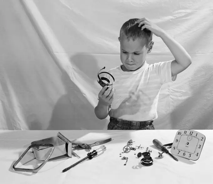 Boy in thoughts holding clock's parts