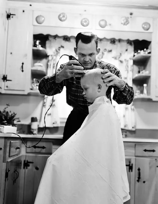 Father shaving son's head