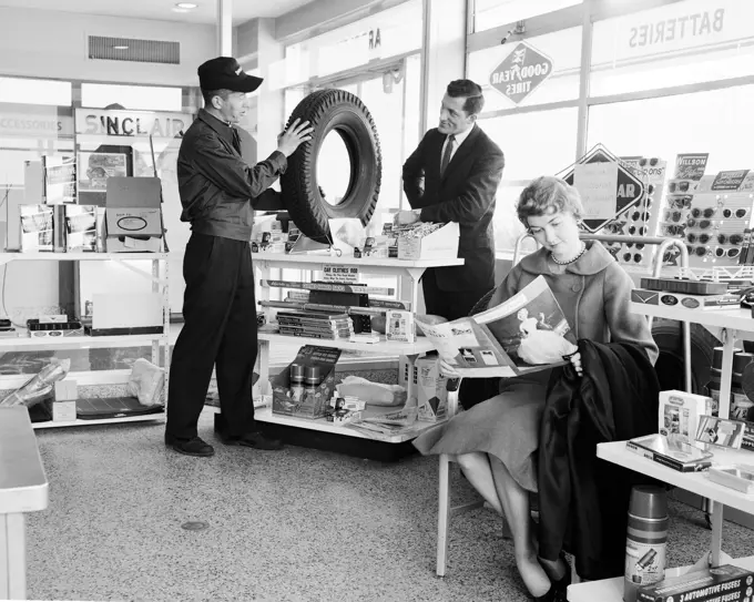 Man buying tire and woman reading magazine