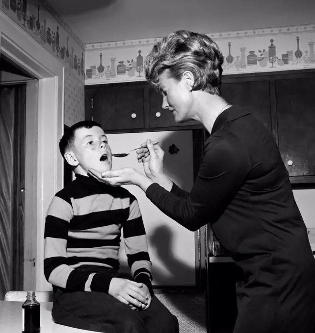 Mother serving medicine to son