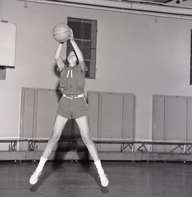 Girl jumping with basketball ball