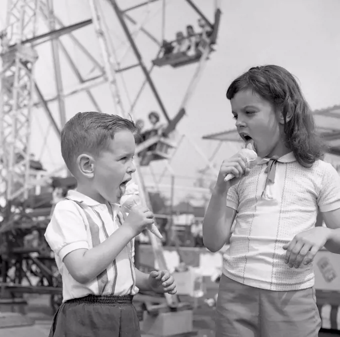 Two kids eating ice-creams in amusement park