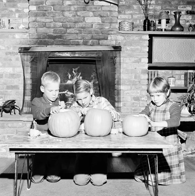 Girl and two boys preparing Jack O' Lantern for Halloween