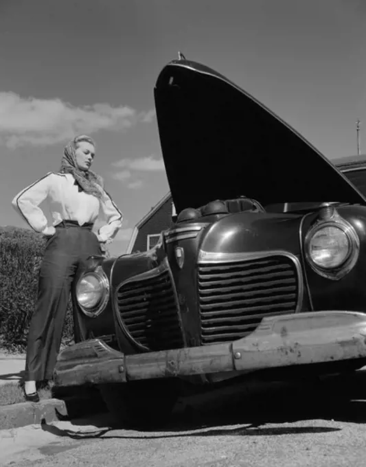 Woman standing by car with open hood