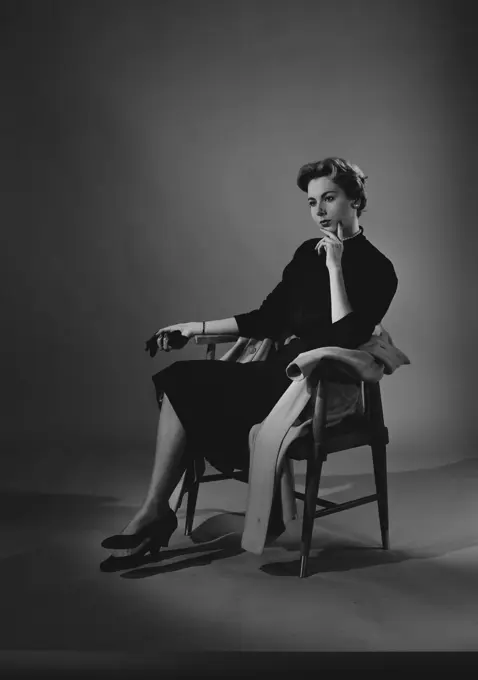 Portrait of thoughtful young woman sitting at chair, studio shot