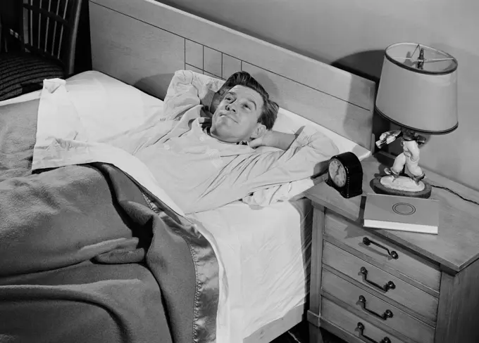 Young man lying in bed smiling