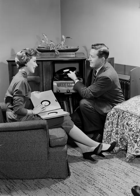 Young couple sitting in living room and listening to music