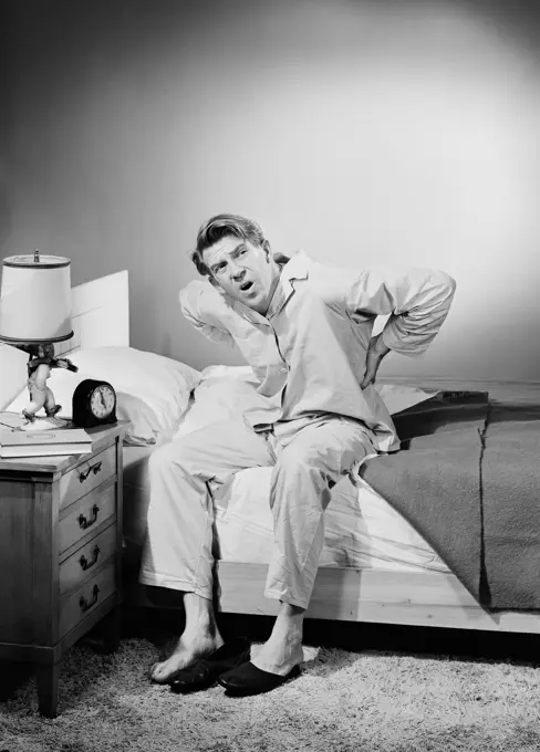 Mid adult man wearing pajamas sitting on bed