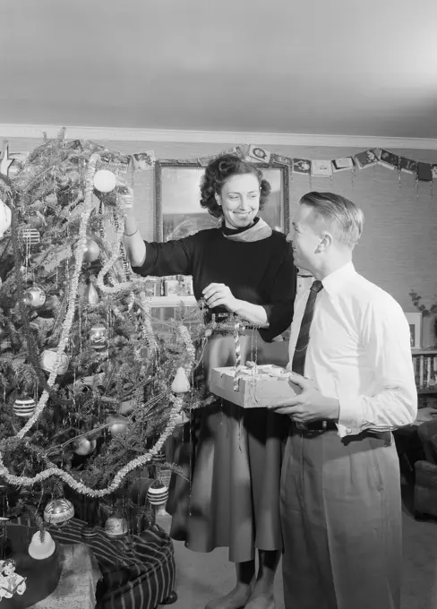 Young couple decorating christmas tree