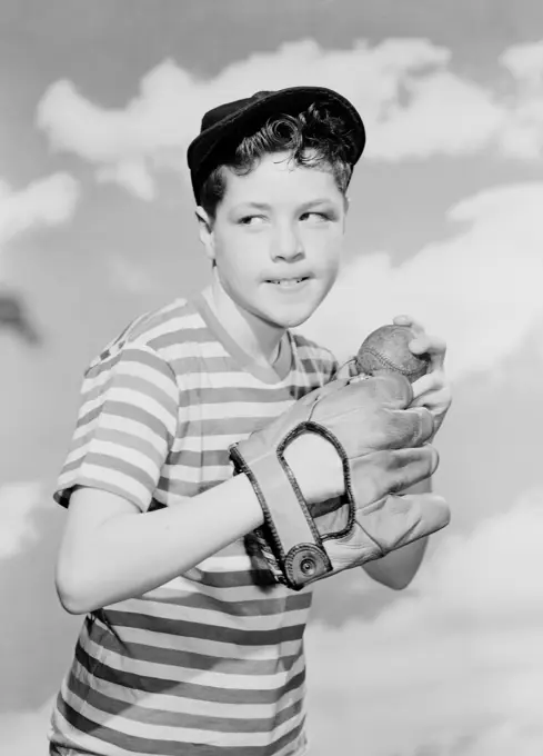 Boy holding baseball against cloudy sky