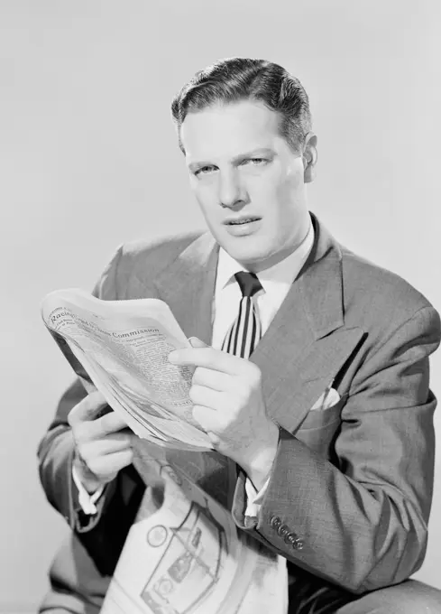 Studio portrait of businessman reading paper