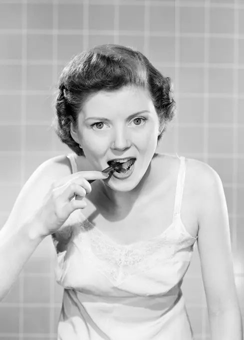 Portrait of woman brushing teeth in bathroom