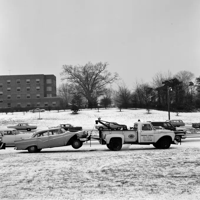 USA, New York State, Long Island, Tow truck pulling wracked car in winter scenery