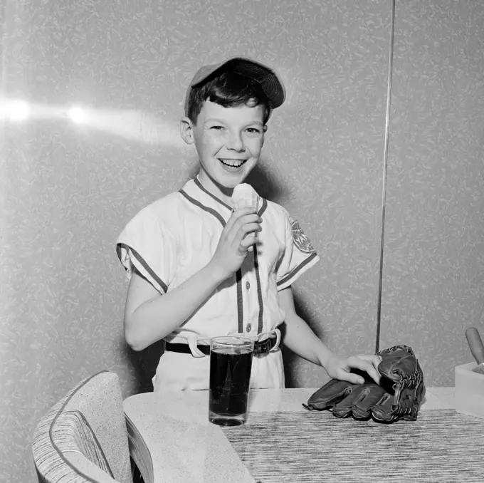 Boy wearing baseball strip eating ice cream