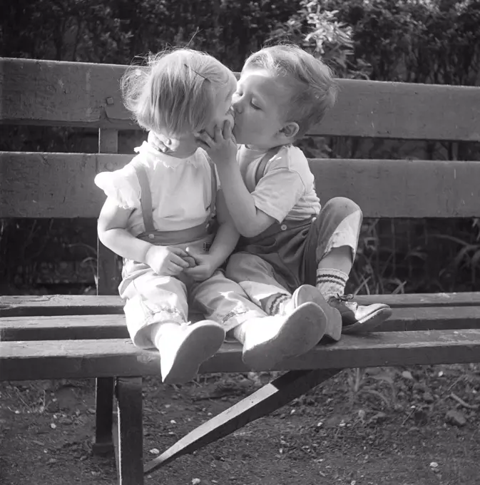 Boy and girl kissing on park bench