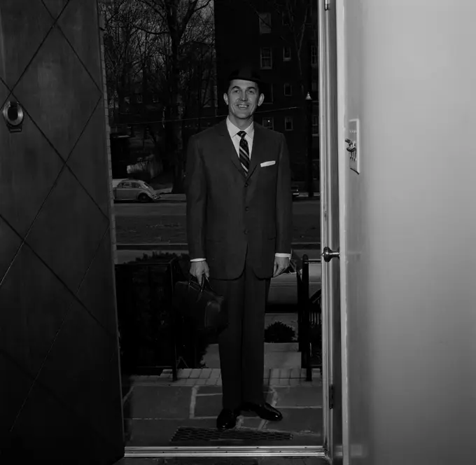 Man wearing suit standing in doorway of house