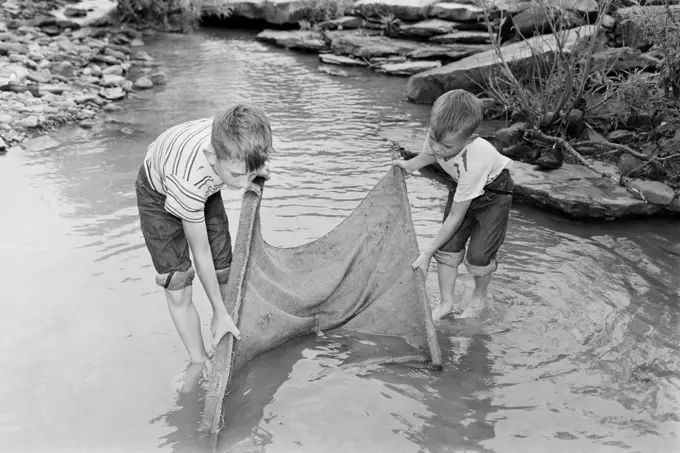 Boys fishing in stream with net