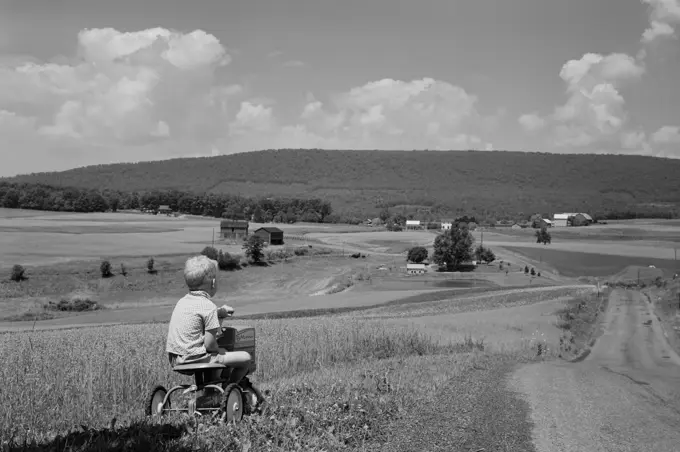 Boy riding tricycle in rural scenery