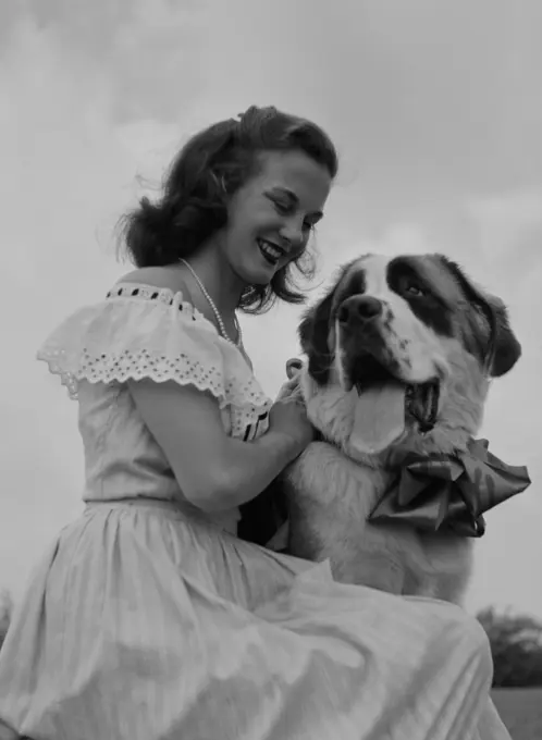 Young woman stroking St. Bernard Dog