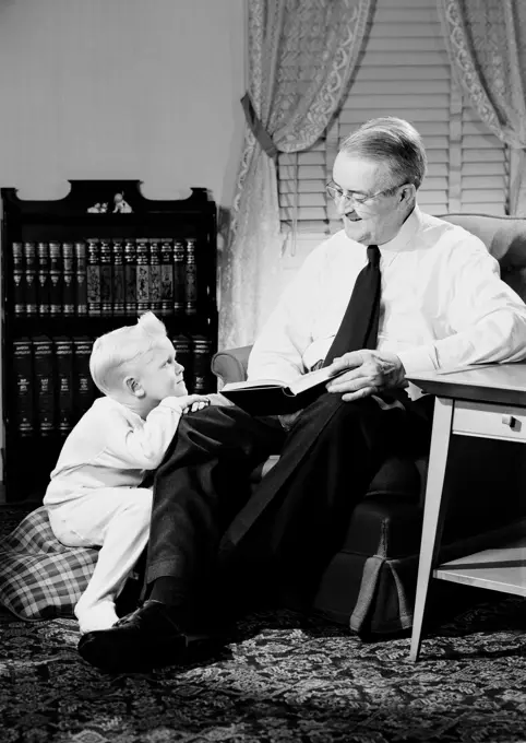 Father reading book with son in living room