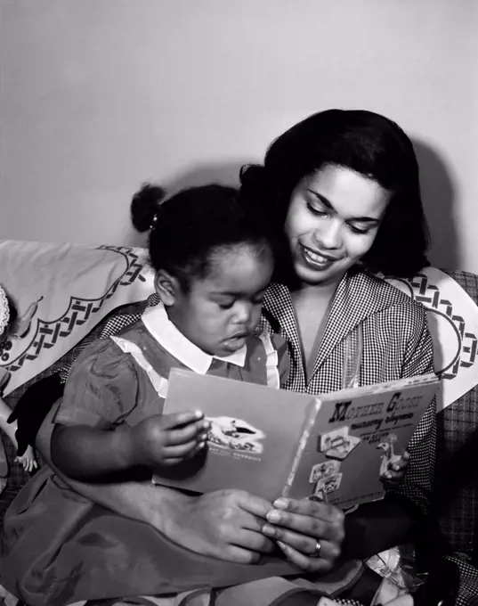 Mother reading book to young daughter