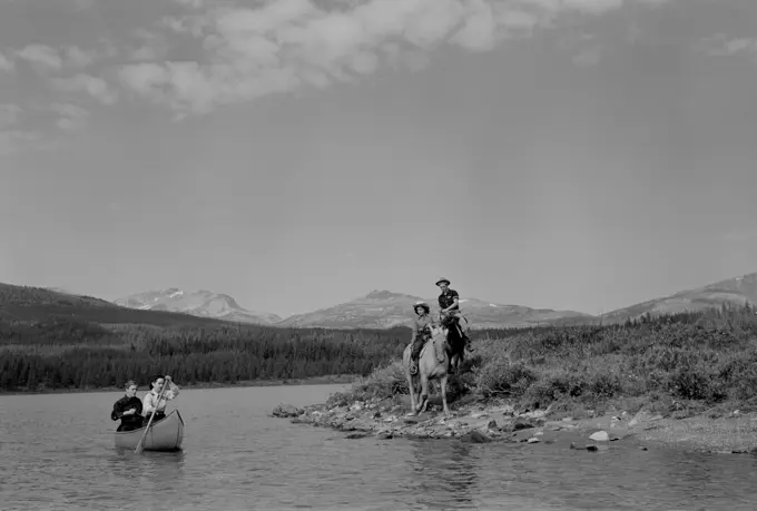 Canada, Canadian Rockies, Maligne Lake, Couple canoeing while two riders are watching from shore