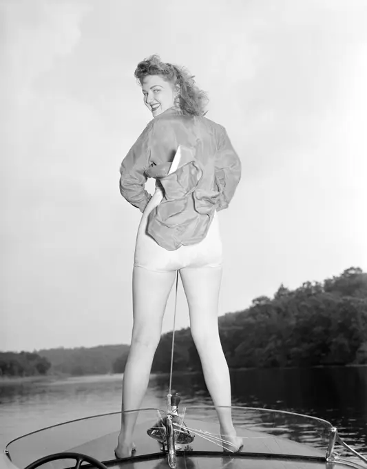 Young woman in swimsuit standing on speed boat