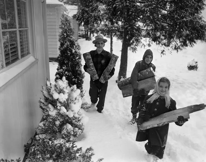 Children with father carrying wood logs in winter