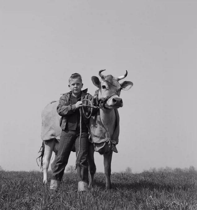 Portrait of boy with cow in field