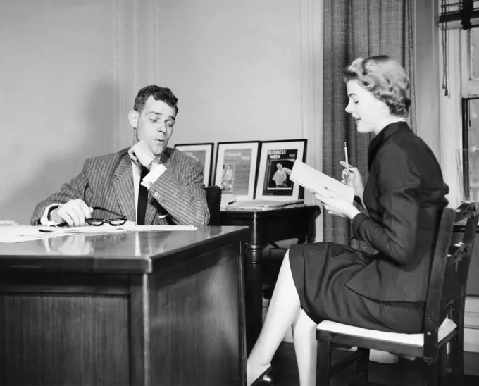 Businessman looking at the legs of his secretary sitting beside him