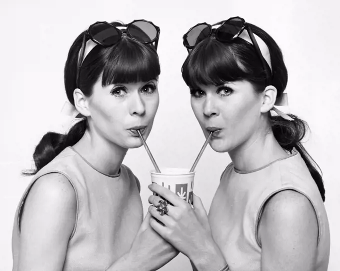 Portrait of twin young women drinking cold drink