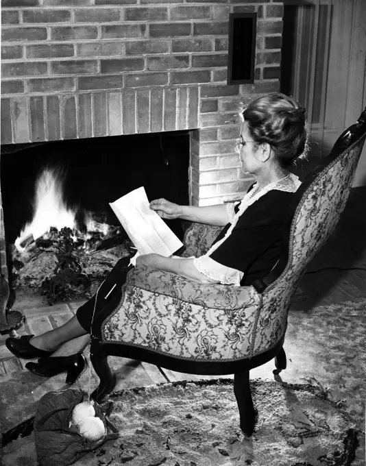 Woman reading letter by fireplace