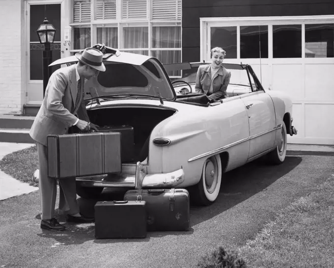 Side profile of a young man loading luggage into a car trunk