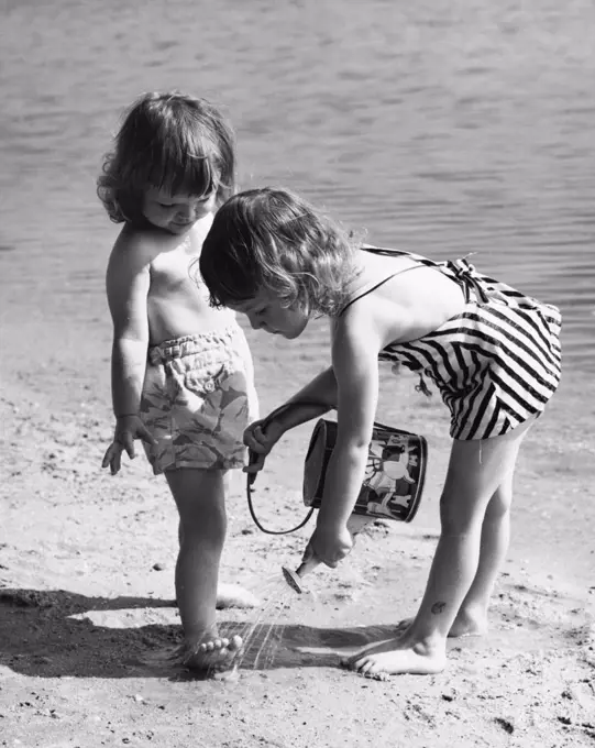 Girl pouring water on the foot of another girl on the beach