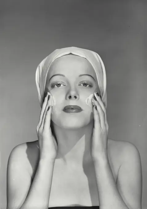 Vintage Photograph. Woman with towel over head washing face as if looking in mirror