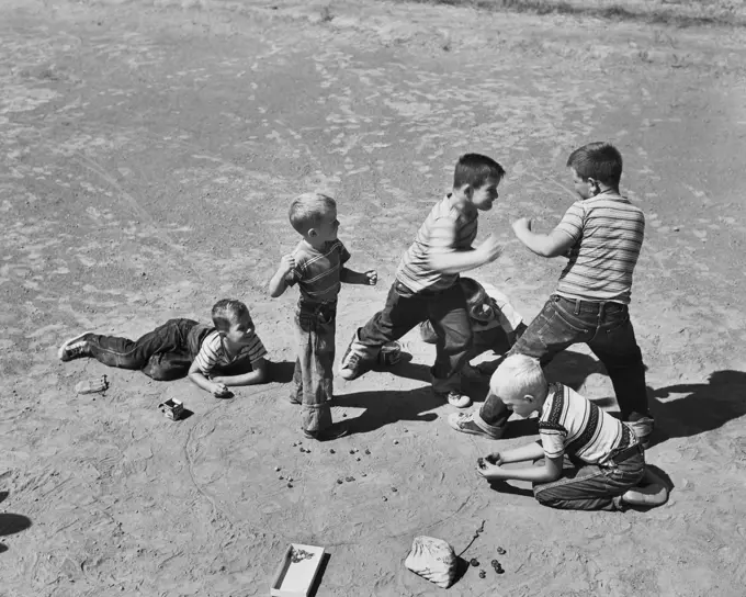 High angle view of boys fighting while playing marbles