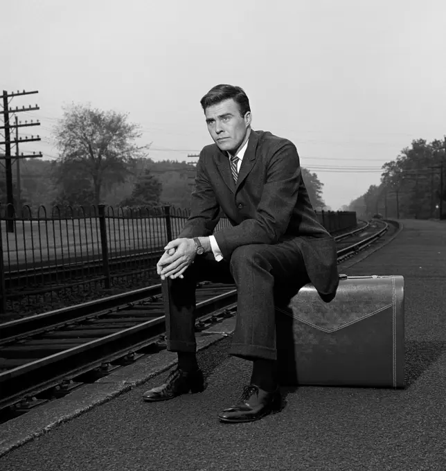 Man sitting on suitcase on platform