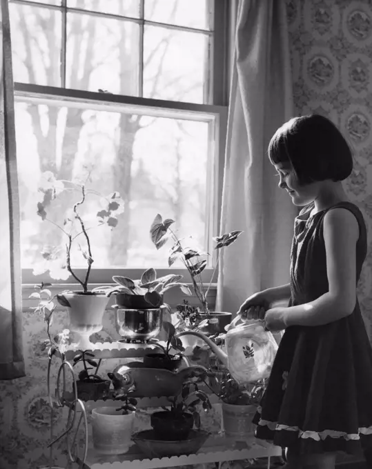 Little girl watering house plants