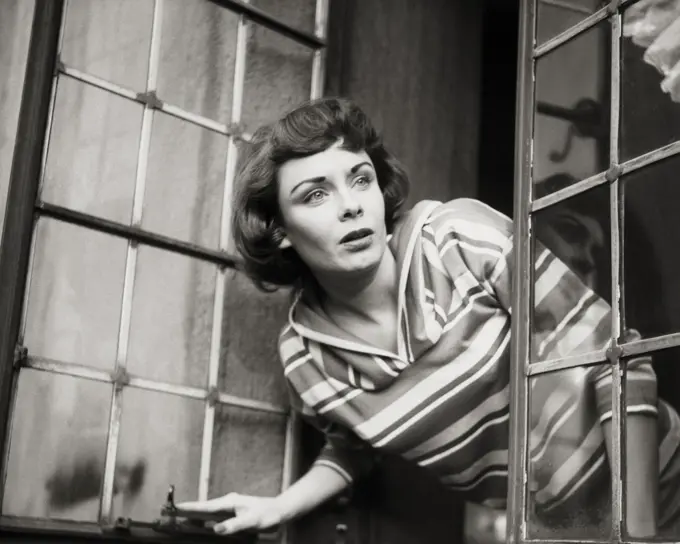 Close-up of a young woman peeking through a window