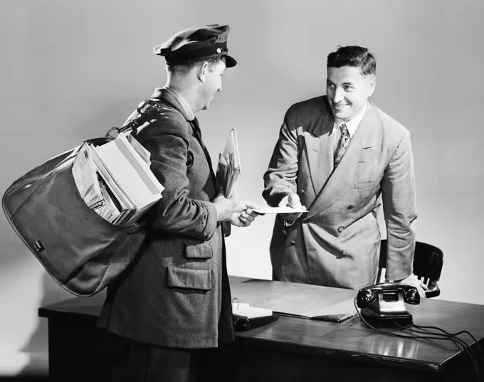 Side profile of a postman giving mail to a businessman