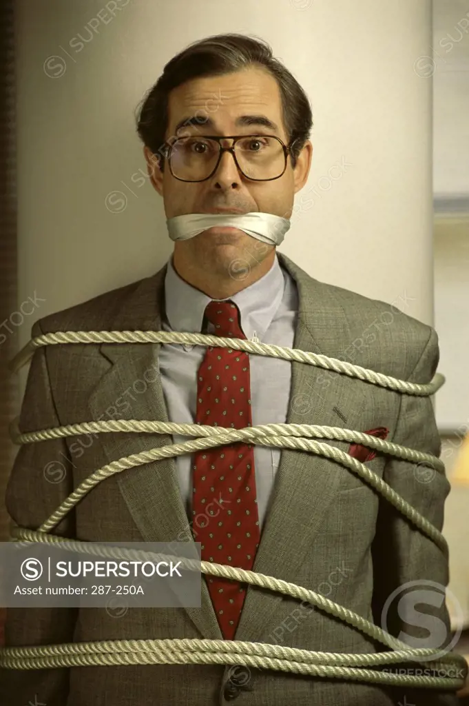 Businessman tied up with a rope and a gag on his mouth