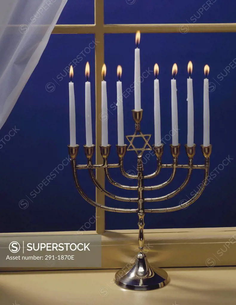 Close-up of burning candles on a menorah at a window