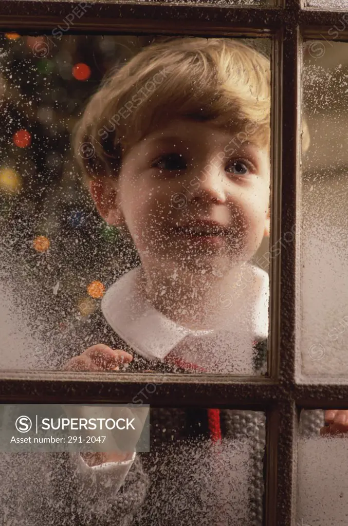 Close-up of a boy looking through a window