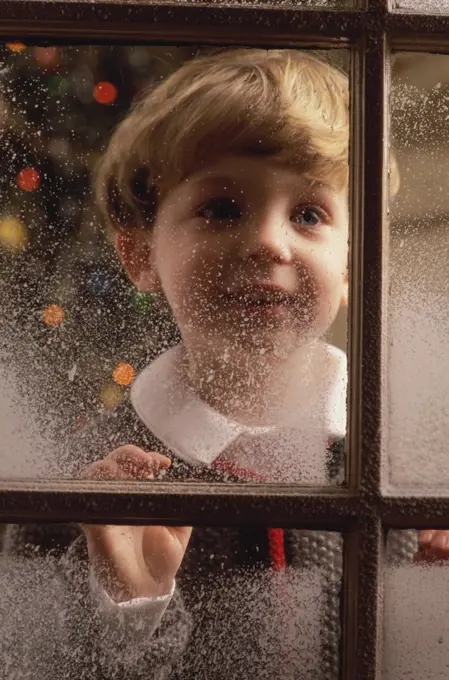 Close-up of a boy looking through a window