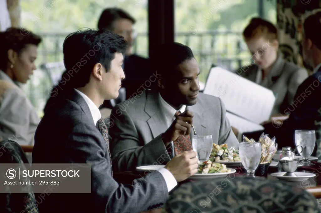 Two businessmen eating food in a restaurant