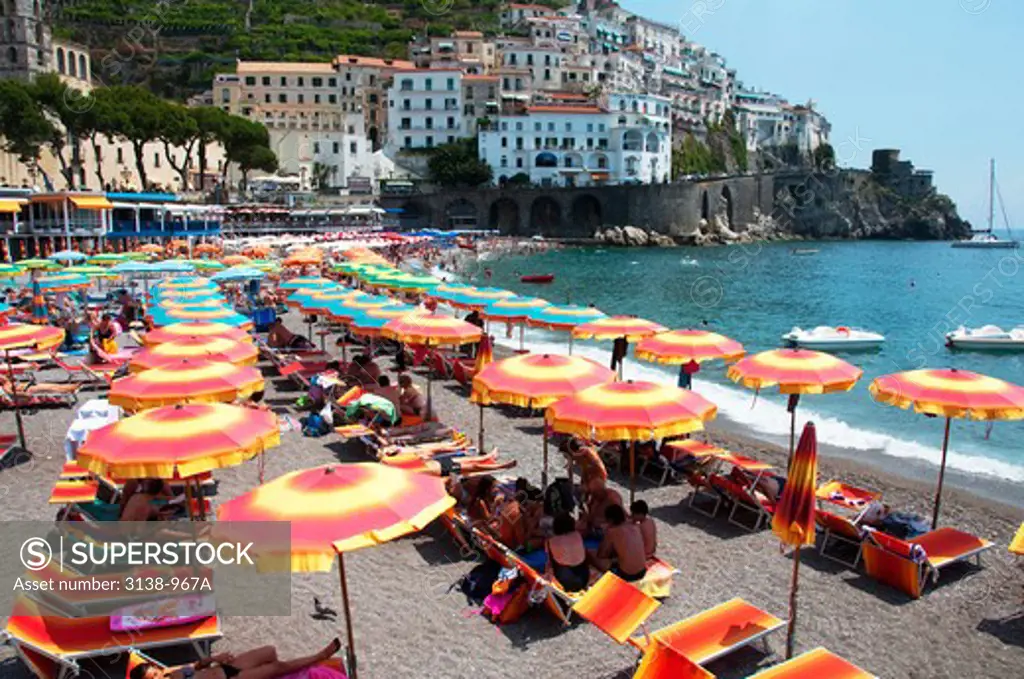 Italy, Amalfi, Sunbathers on beach under colorful sunshades