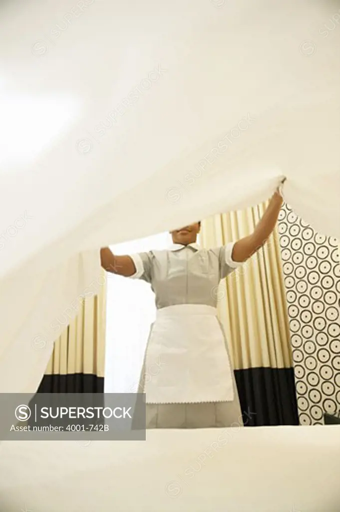 Housekeeper changing the sheet of a bed in a hotel room