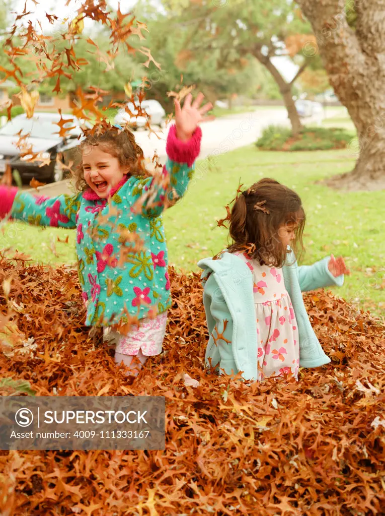Little girls playing in the autumn leaves