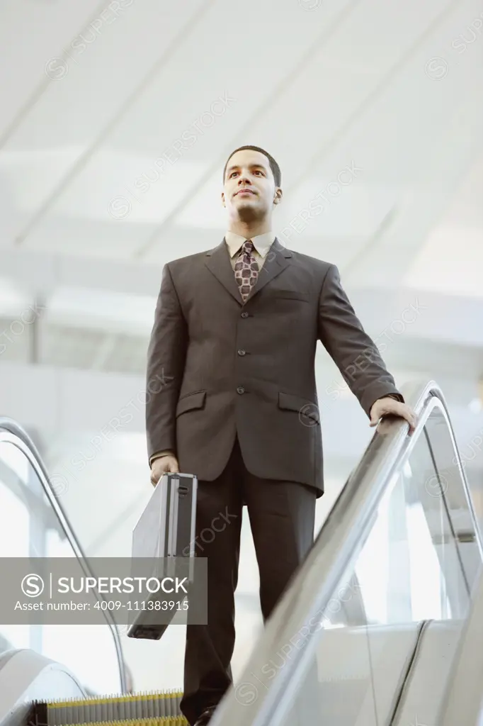 Hispanic businessman carrying briefcase on escalator