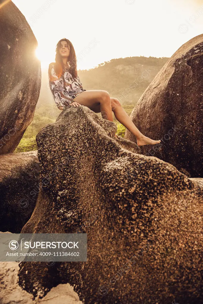 Hispanic woman sitting on boulder